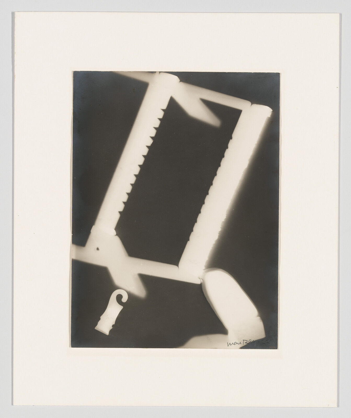A high-contrast photogram showing a saw frame with serrated blade and curved handle.