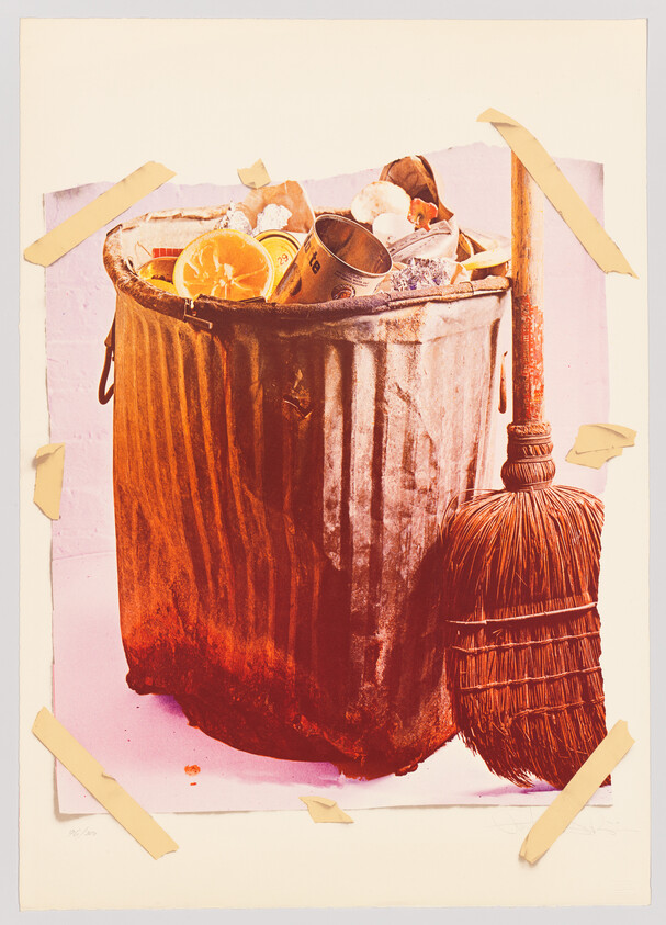 A metal trash can overflowing with food and cans next to a straw broom.