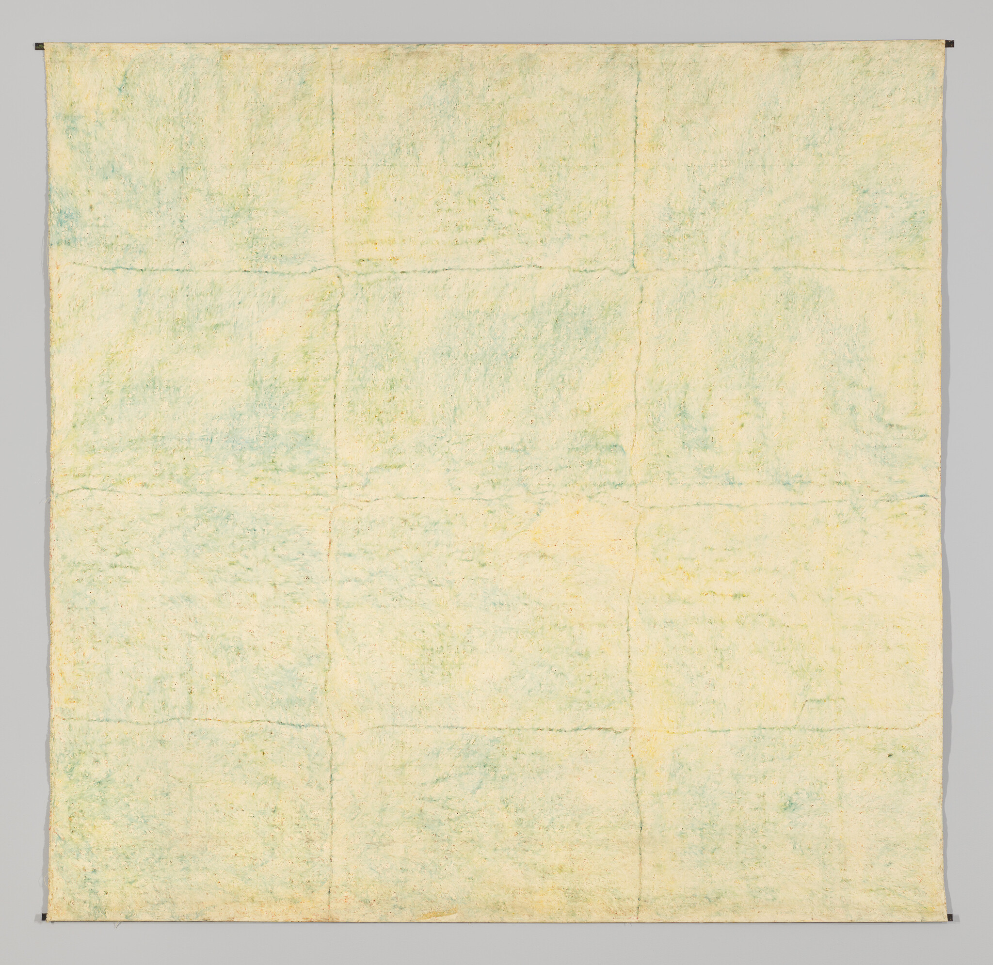 Large pale quilt with faint green shading and nine-panel seam grid hanging against a gray background.