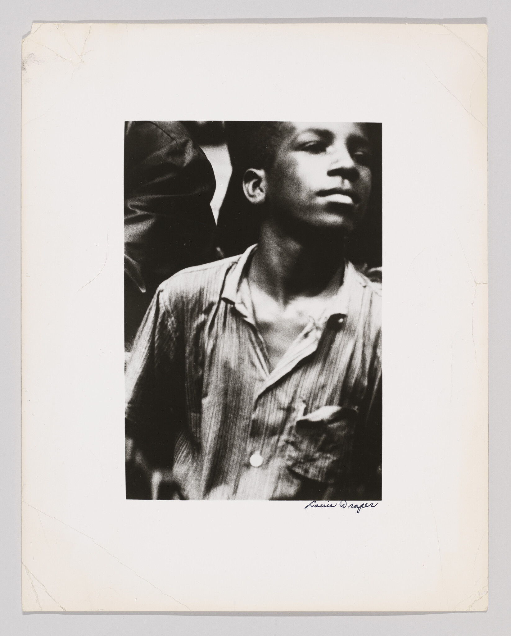 Young boy in a striped shirt looks upward with a thoughtful expression.