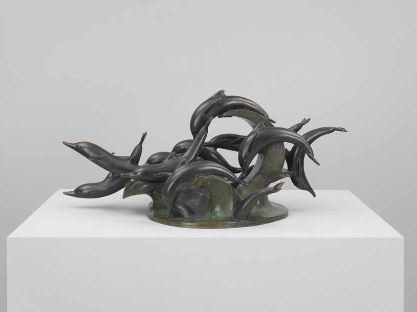 Bronze sculpture of dolphins leaping and twisting through stylized waves on a pedestal.