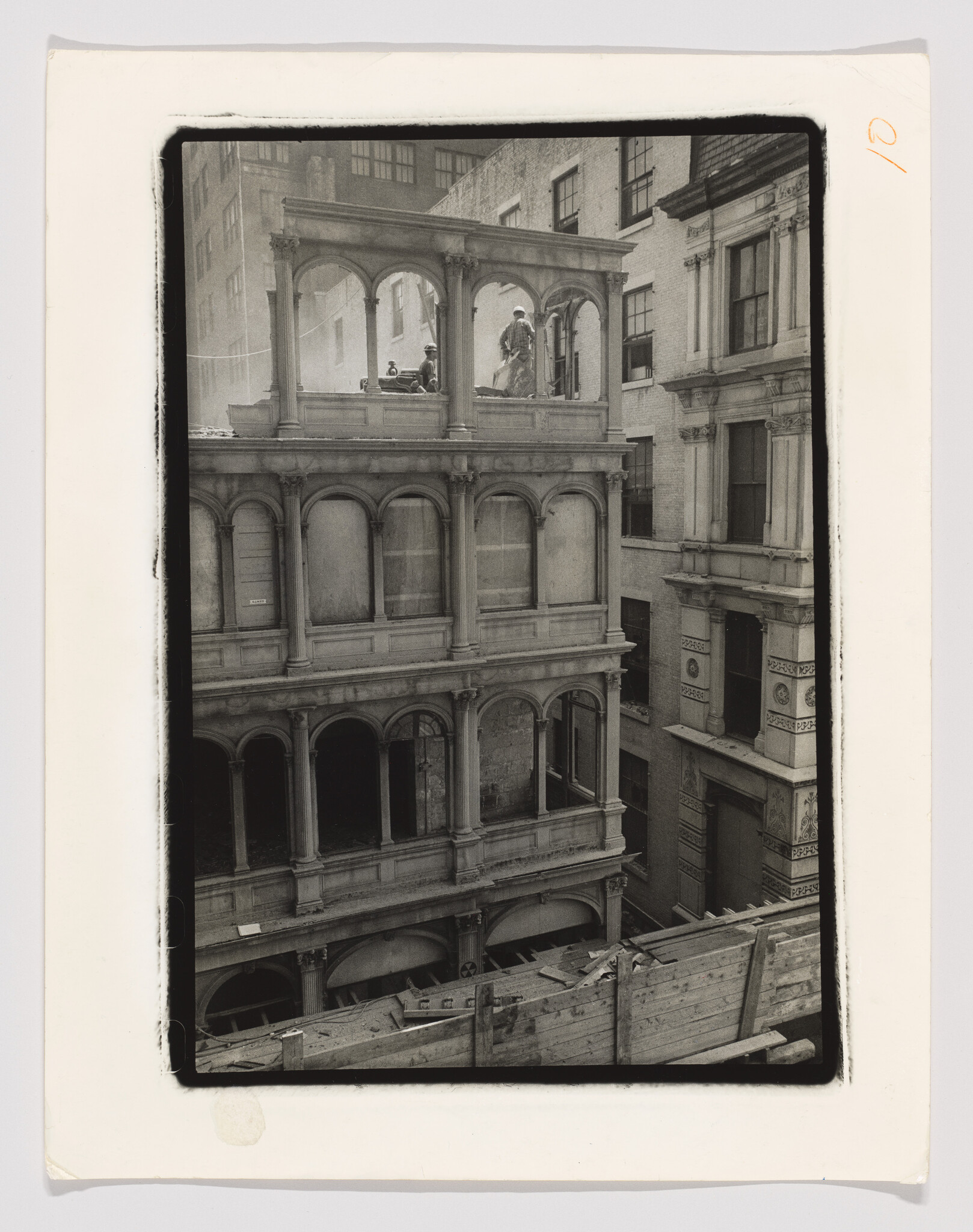 Workers stand on the rooftop of an old arched building amid construction debris.