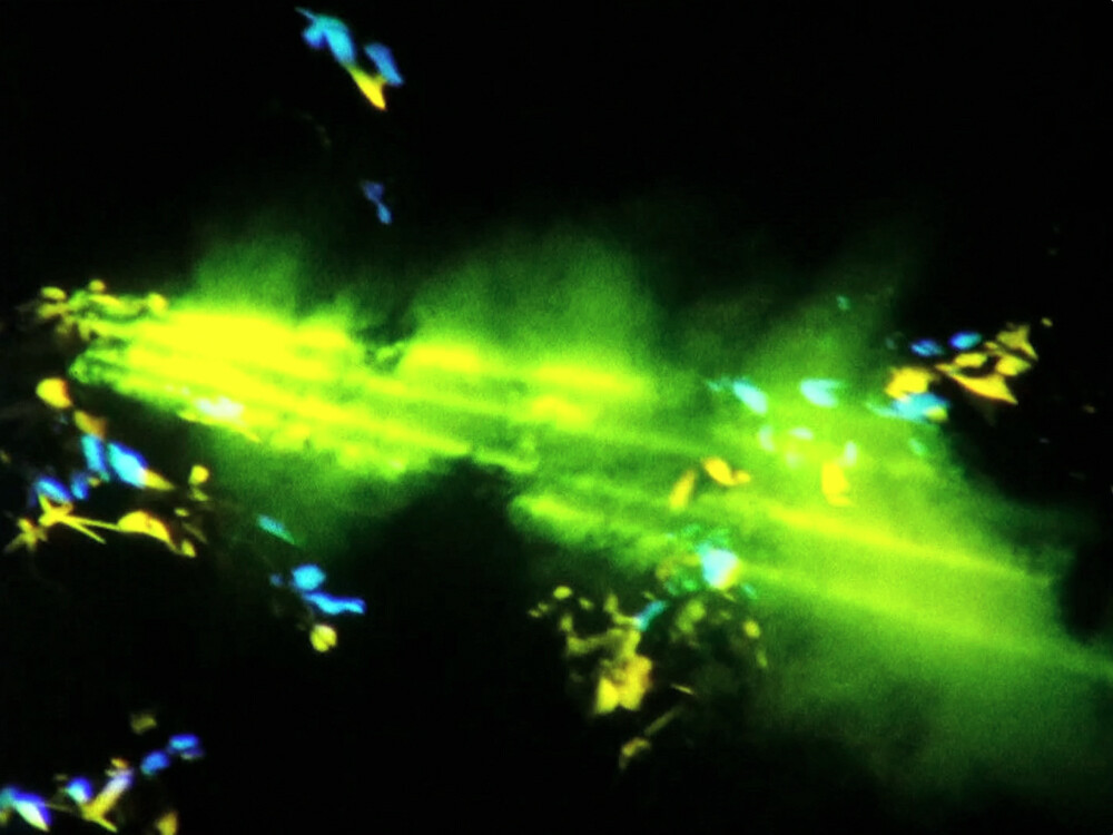 Bright neon green streaks with scattered blue and yellow particles against a dark background.