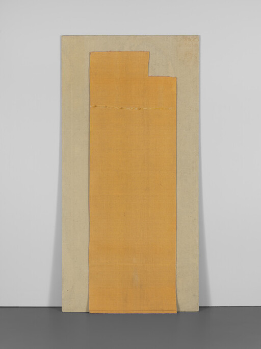 A tall beige board leaning against a wall with a long orange fabric panel attached.