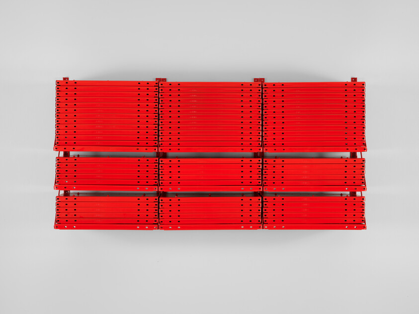 Nine stacks of red metal beams arranged in a rectangular grid against a white background.