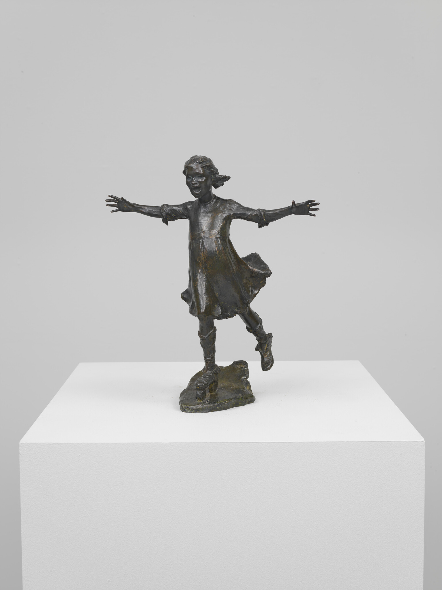 Bronze sculpture of a young girl balancing on one foot with arms outstretched.