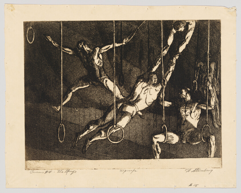 Three male acrobats swing and hang from gymnastic rings in a dark performance.
