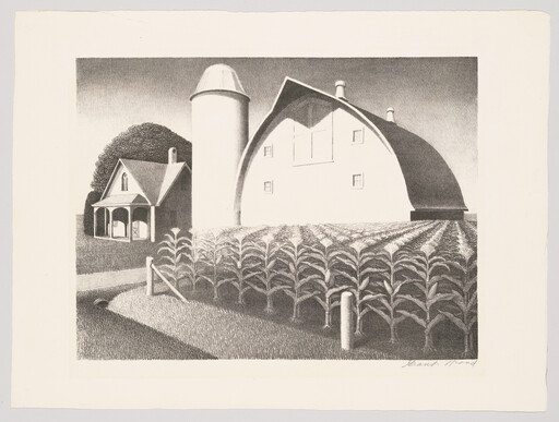 A white curved barn and silo stand beside a farmhouse next to neatly planted rows of corn.