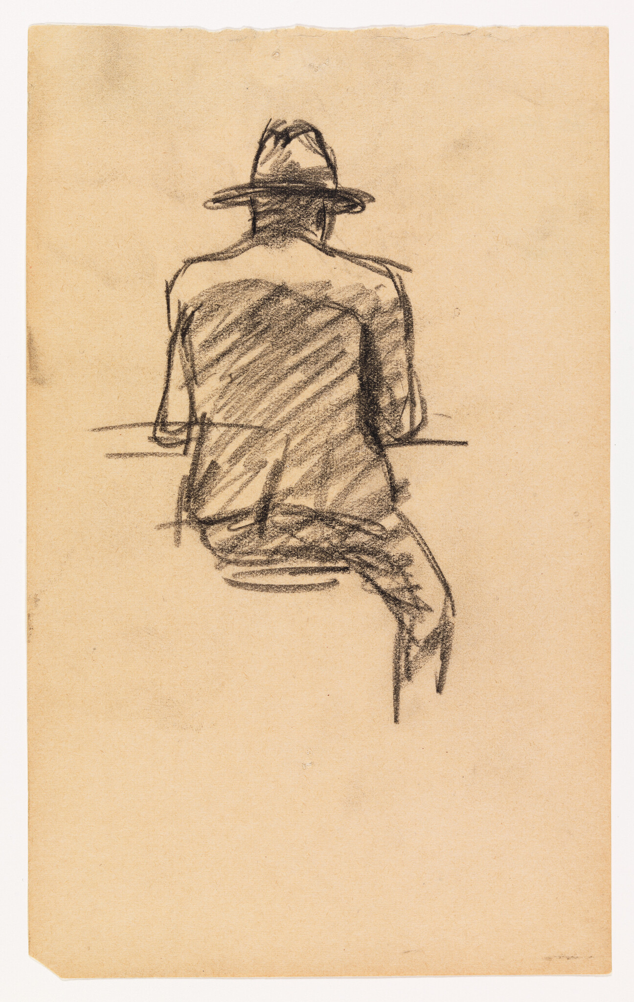 Man wearing a hat sits on a stool at a counter, shown from behind.