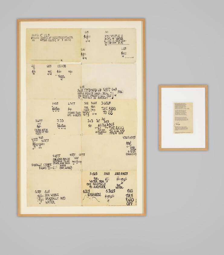 Two framed handwritten sheets on a gray wall, one large sheet with sketches and notes.