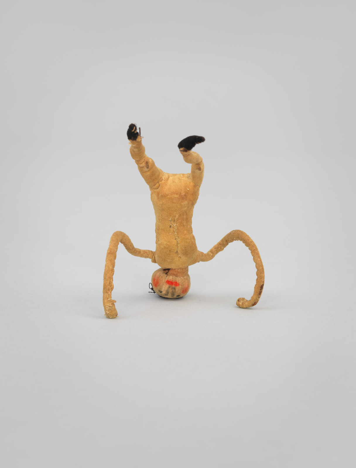 Small, flexible toy figure doing a headstand with arms and legs bent outward.