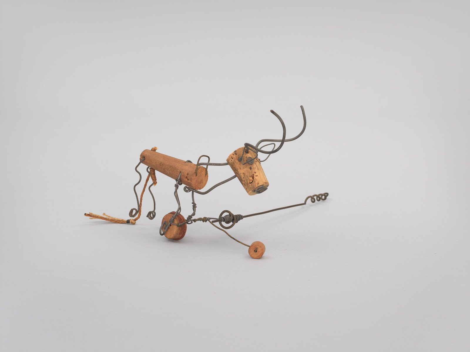 Small wire and cork sculpture resembling a deer with curled metal antlers and wooden bead legs.