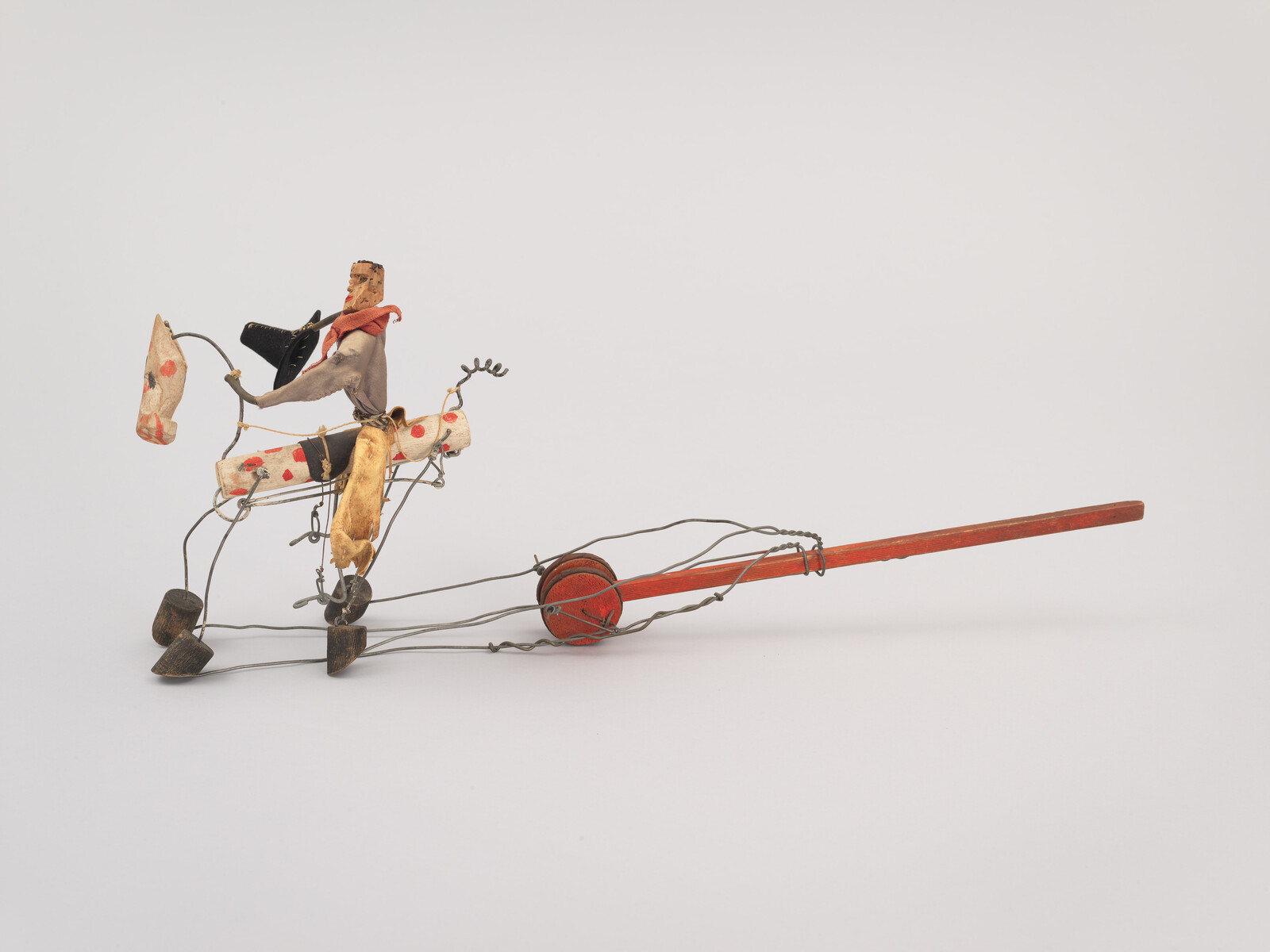 Small handmade wire and fabric horse and rider toy attached to a long red wooden handle.