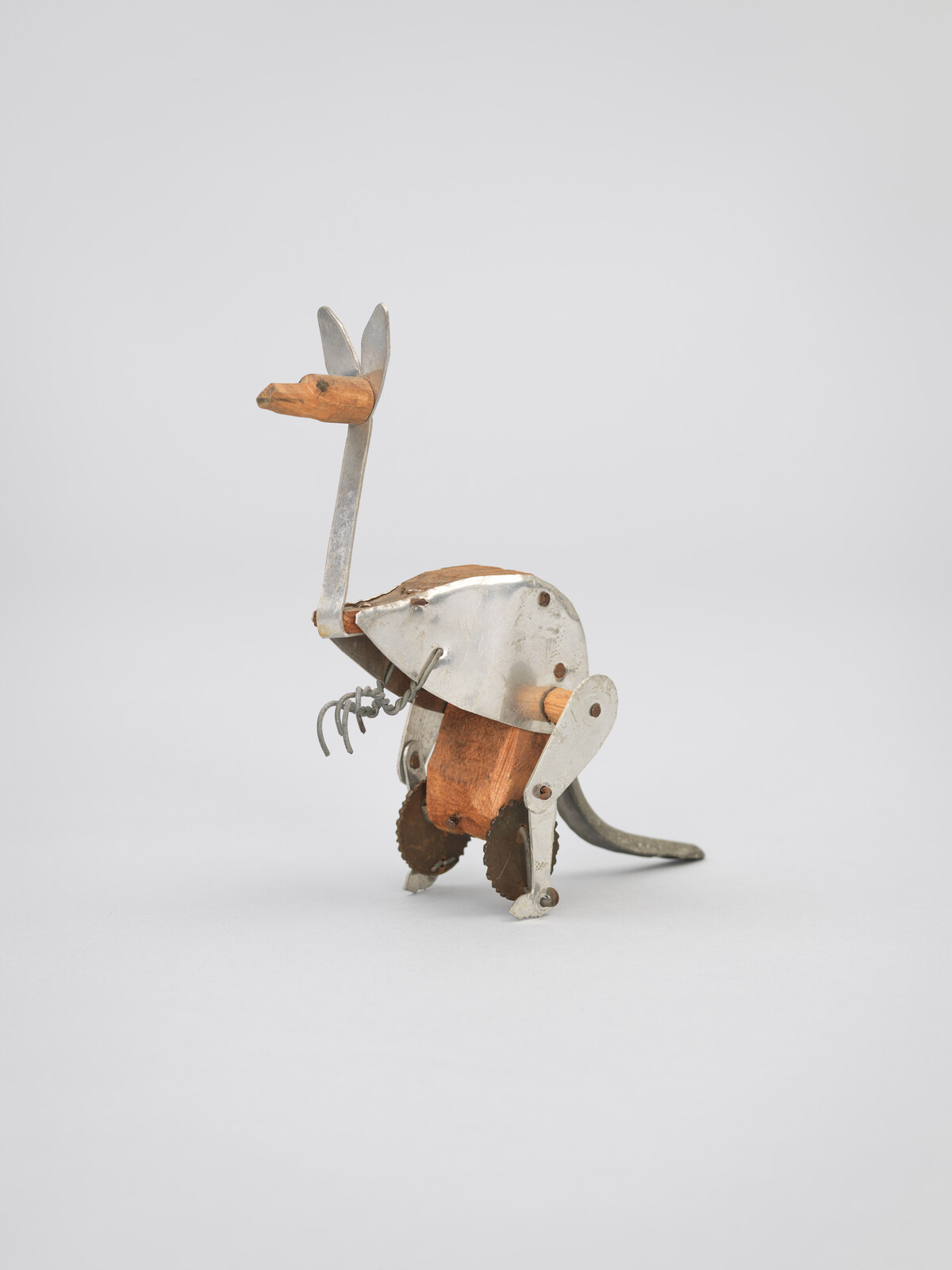 A small handmade metal and wood mechanical kangaroo toy with saw-blade feet and wire claws.