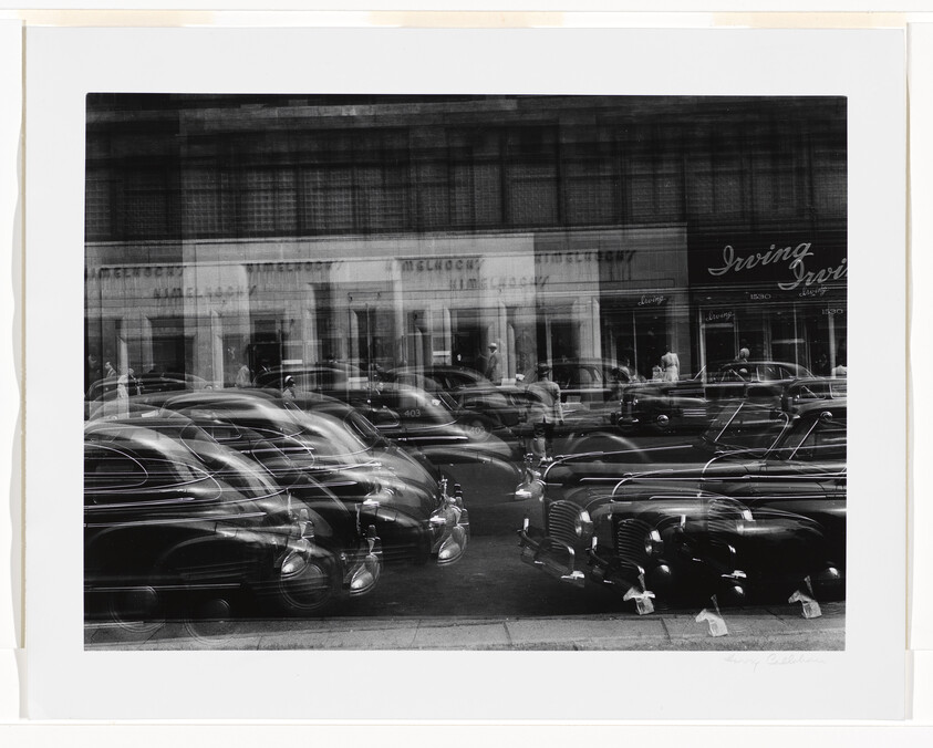 Multiple parked and moving cars blur across a busy city street in a layered, double-exposure photograph.