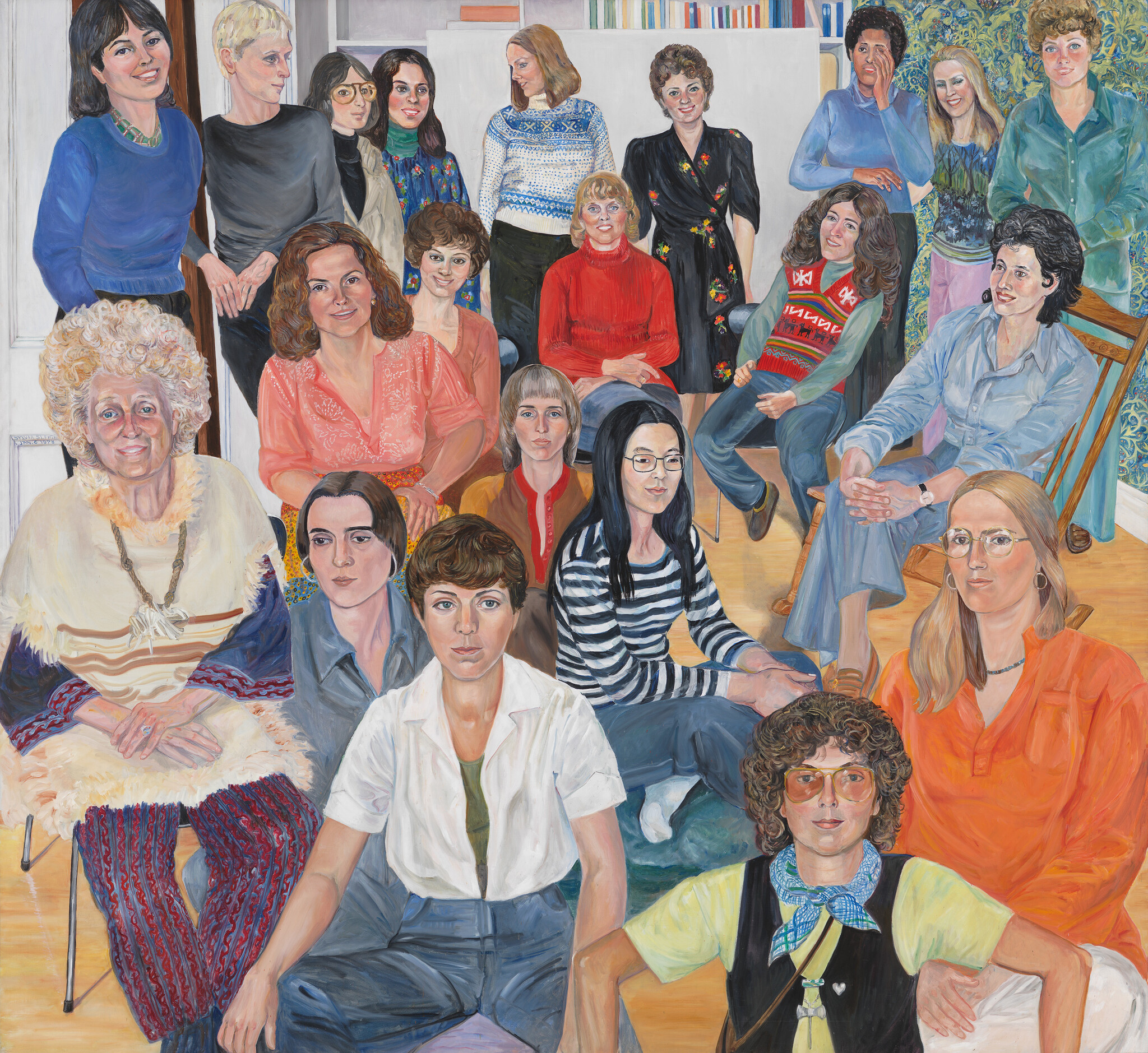 A group of women of different ages sit and stand together in a brightly lit room, facing forward.