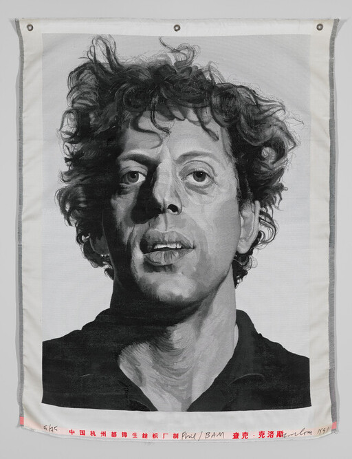 Large black-and-white painted portrait of a curly-haired man hanging on fabric.