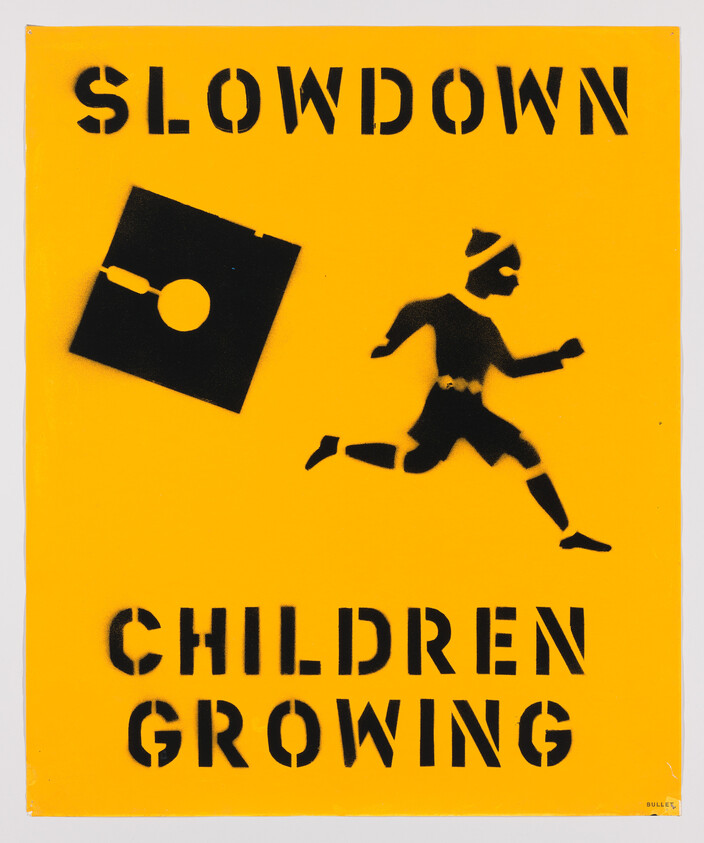 Yellow sign with black stencil art of a running child and text "SLOWDOWN CHILDREN GROWING."