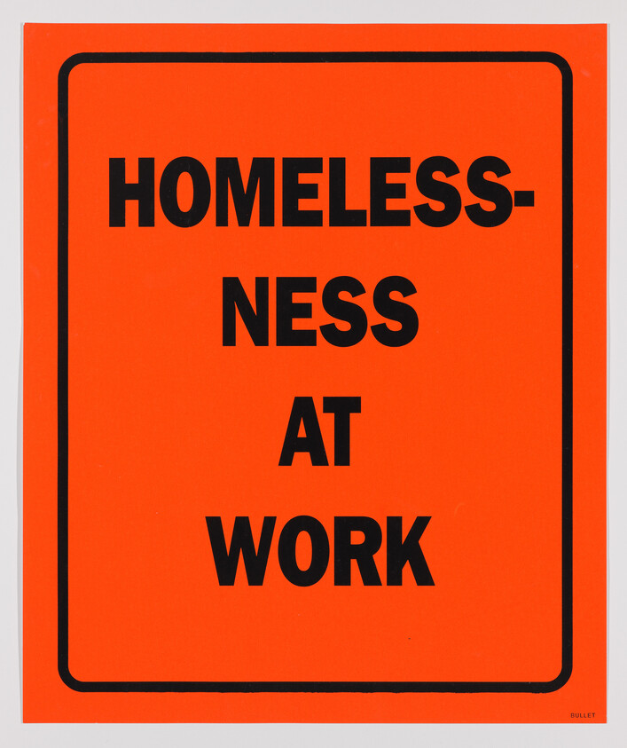 A bright orange sign with bold black text that reads "HOMELESSNESS AT WORK," with the word "HOMELESSNESS" broken into two lines. The sign has a black border and is reminiscent of a caution or warning sign. The bottom right corner features the word "BULLET" in small print.