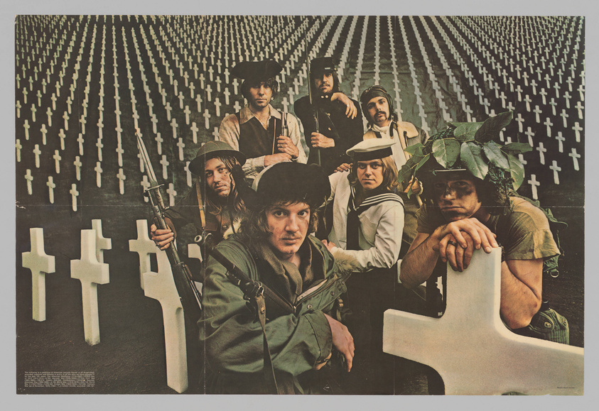 A vintage poster featuring a group of seven individuals dressed in a mix of military and unconventional attire, posing solemnly in front of a backdrop with rows of white crosses. The person in the foreground is seated and leaning on a cross, while others stand or kneel, some holding weapons and one wearing a helmet with foliage. The image conveys a strong anti-war sentiment, characteristic of the counterculture era.