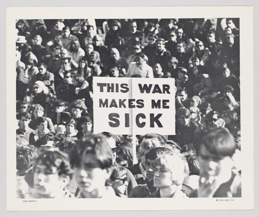 Crowd of protesters holding a sign that reads "This war makes me sick."
