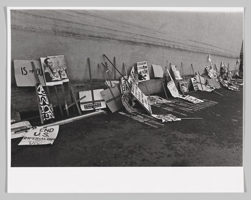 Many protest signs and wooden placards lean against a wall, left after a demonstration.
