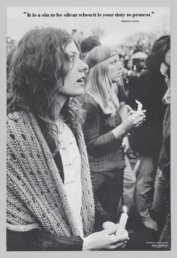 Two women hold candles and participate in a protest beneath a quote about duty to speak out.