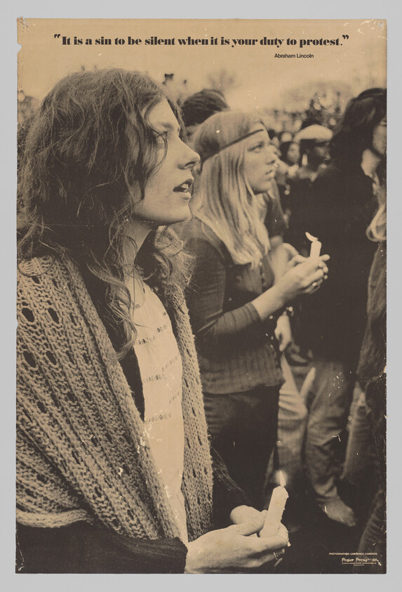 Young woman holding a lit candle during a protest vigil, other participants visible behind her.