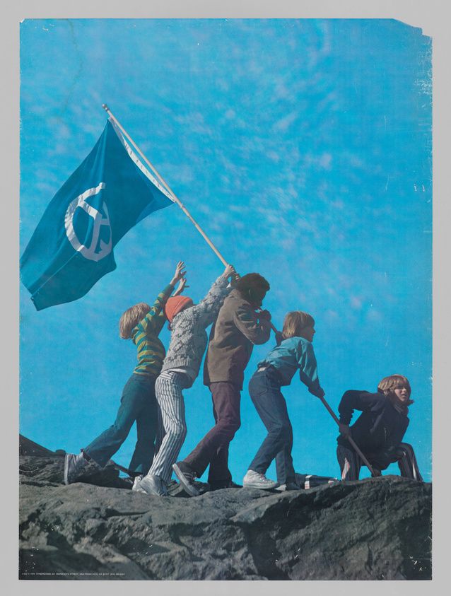 A group of five youths in casual attire is seen raising a flag with a peace symbol on a rocky outcrop against a clear blue sky. The image has a vintage look with visible creases and wear, suggesting it might be an older photograph or poster.