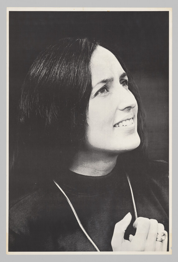 A woman with long dark hair looks upward and smiles while holding a necklace near her chest.