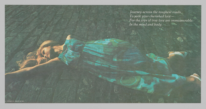 Woman in a blue-green dress lies stretched out on cobblestones with arms extended.