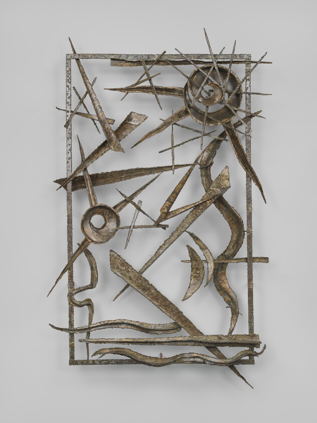 Metal sculpture with jagged, abstract shapes and spirals arranged inside a rectangular frame, suggesting movement and energy.