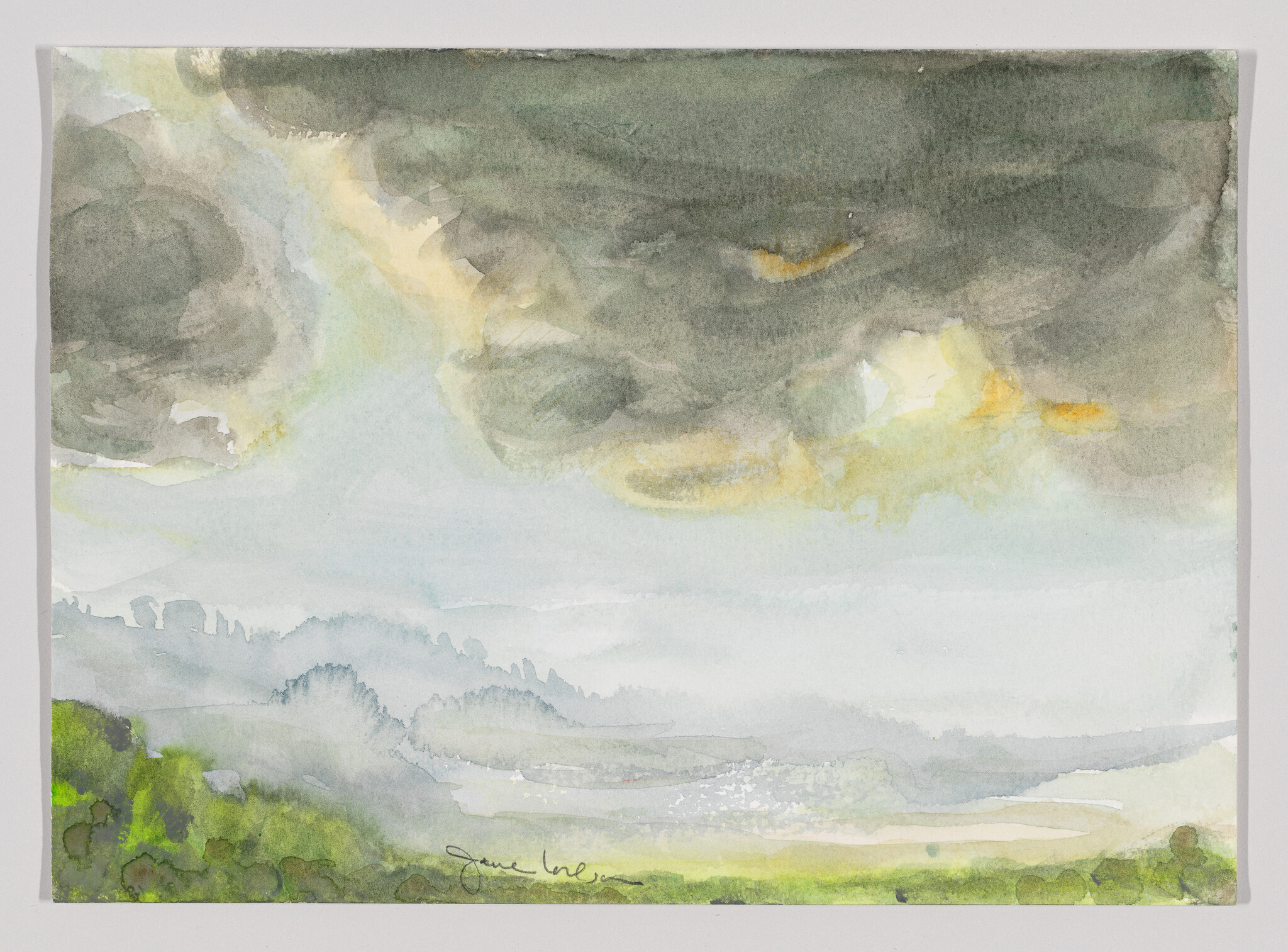 Storm clouds gather over misty rolling hills with bright green foreground.