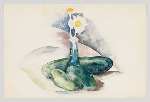 Small blue vase holds two white daisies standing among large smooth green stones.