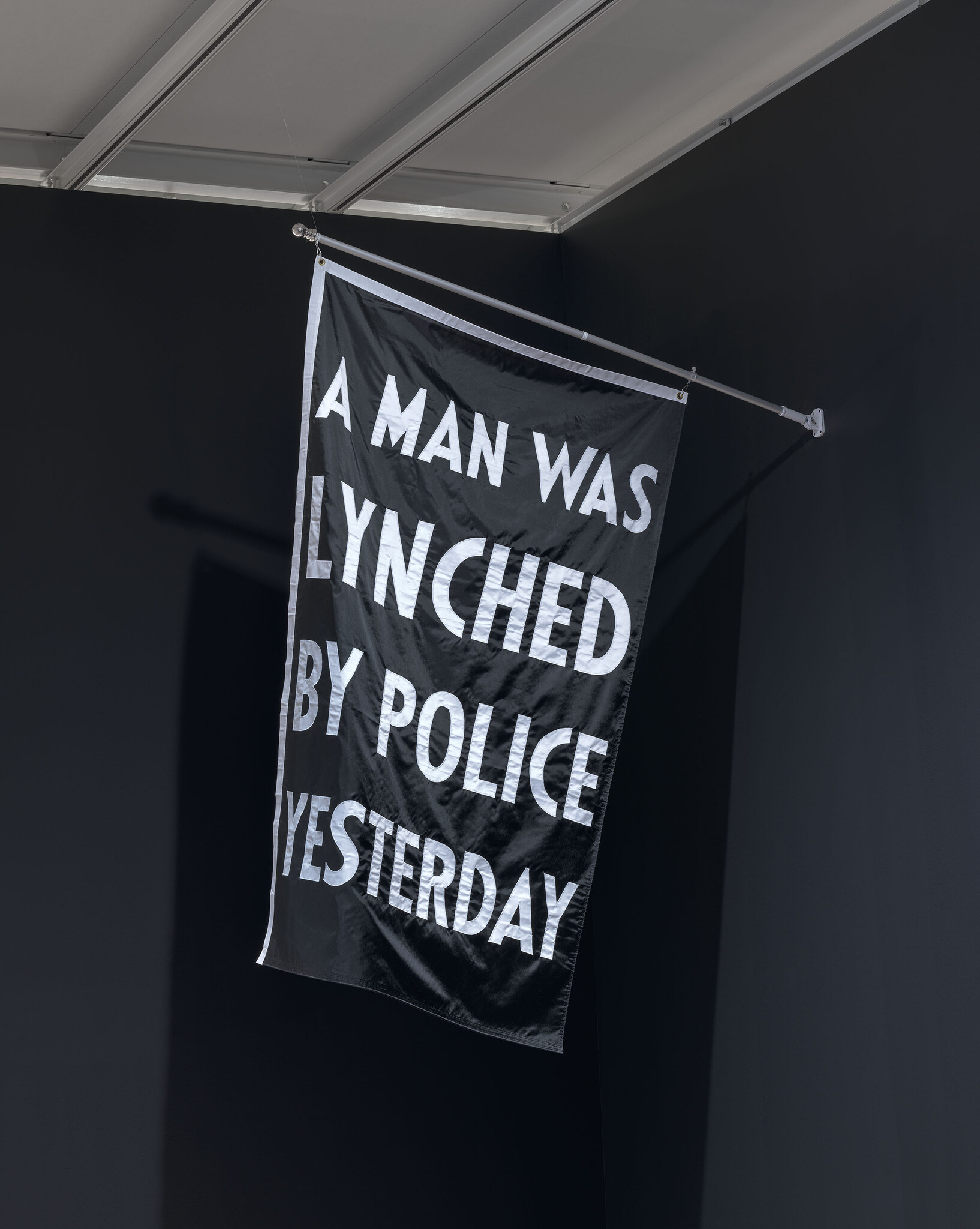 A black flag with white words reading A MAN WAS LYNCHED BY POLICE YESTERDAY.