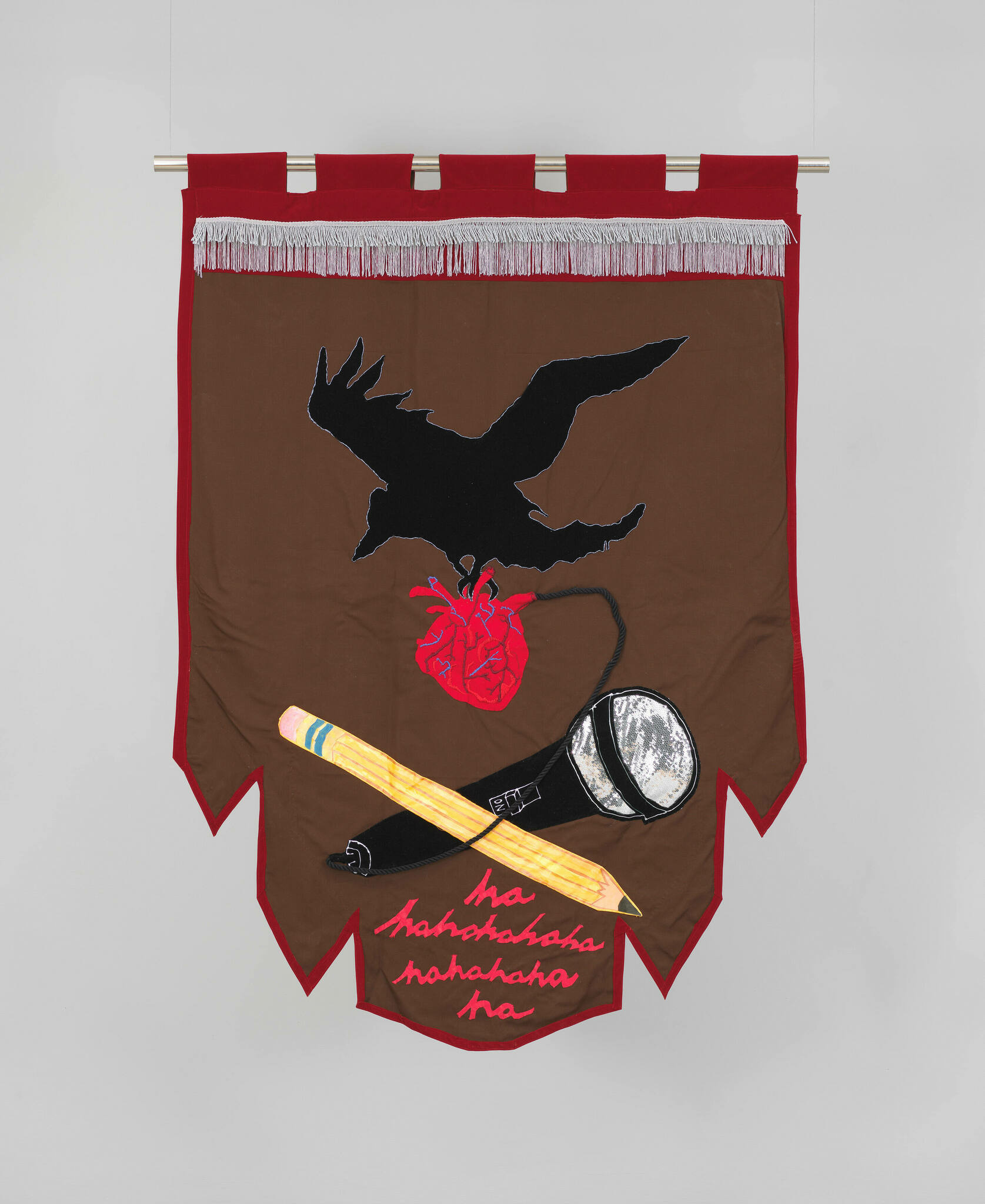 Fabric banner with black bird grasping anatomical heart above pencil and microphone. Text in cursive reads "hahaha."