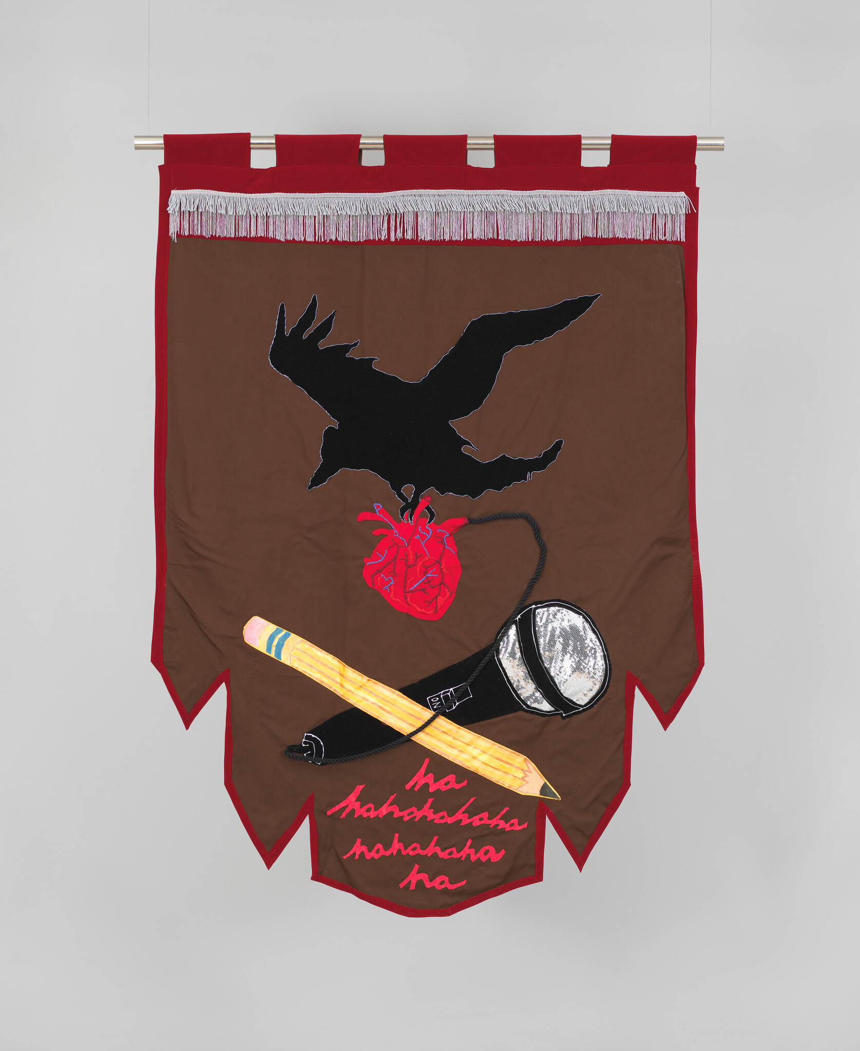 Fabric banner with black bird grasping anatomical heart above pencil and microphone. Text in cursive reads "hahaha."