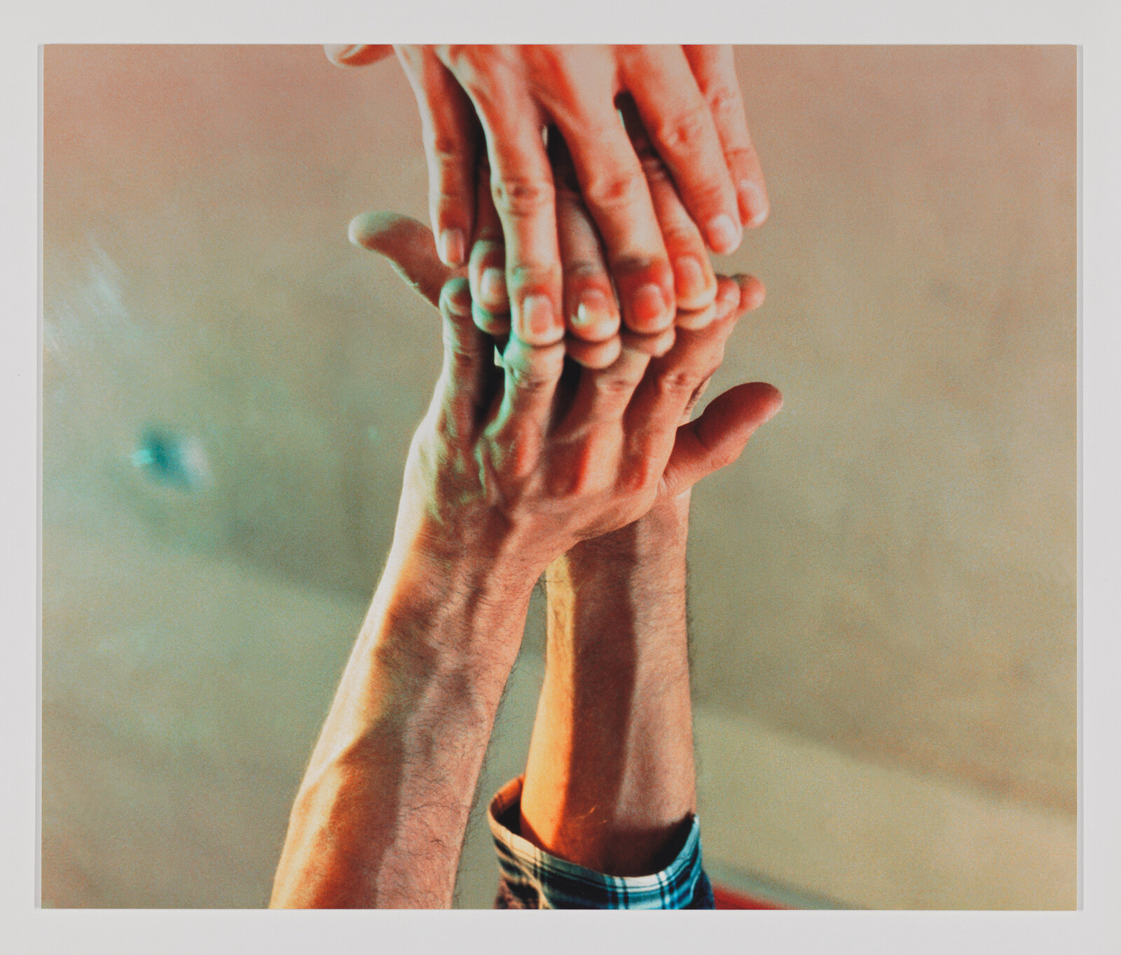 Three hands stacked together with two arms reaching upward in a supportive gesture.