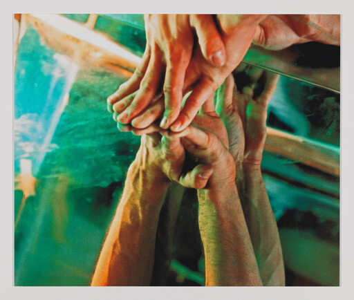 Two hands gently clasp another person's feet reflected in a green-tinted mirror.
