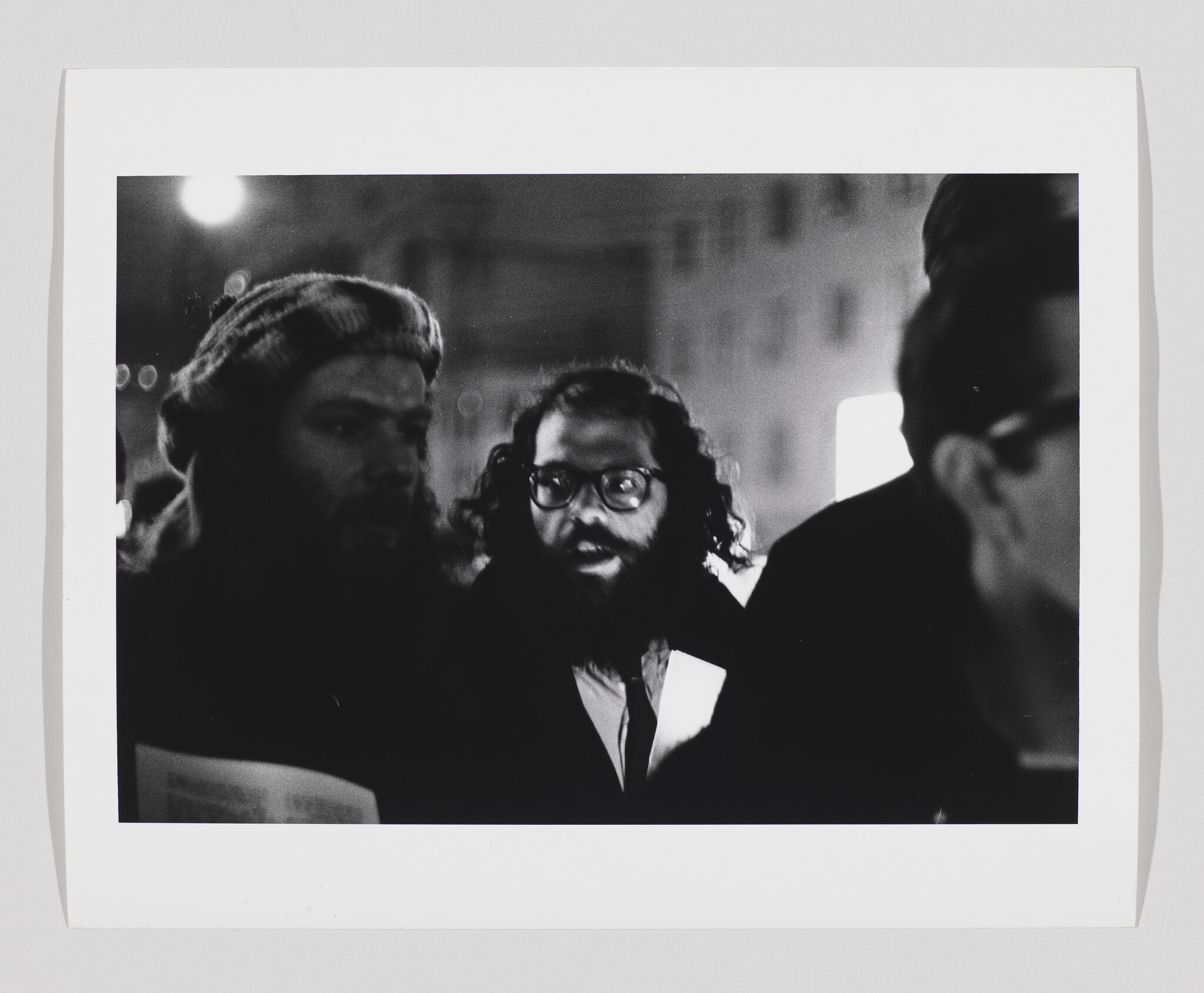 Bearded man with glasses speaking among a small group of people at night.