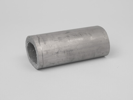 Hollow metal cylinder with rough inner edge resting on a flat surface.