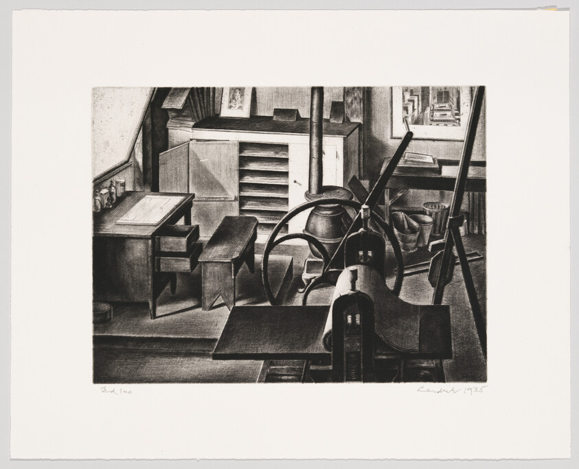 A small printmaking workshop with an ink roller press, worktable, storage drawers, and tools.