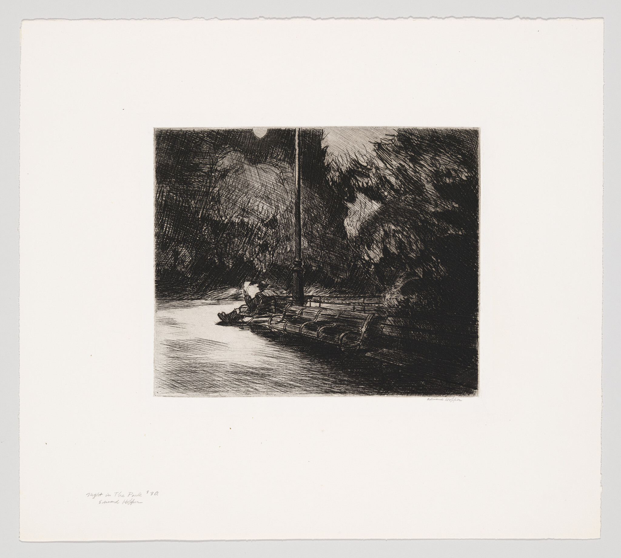 A lone person sits on a park bench under a tall lamppost at night.
