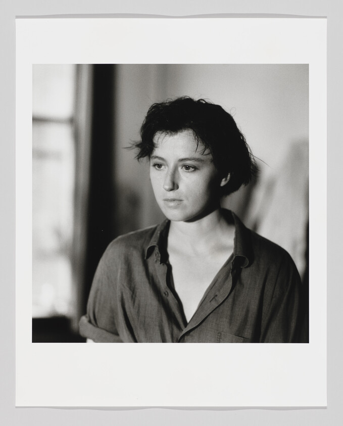 Young woman with short dark hair looking thoughtfully to the side while wearing a loose button-up shirt.