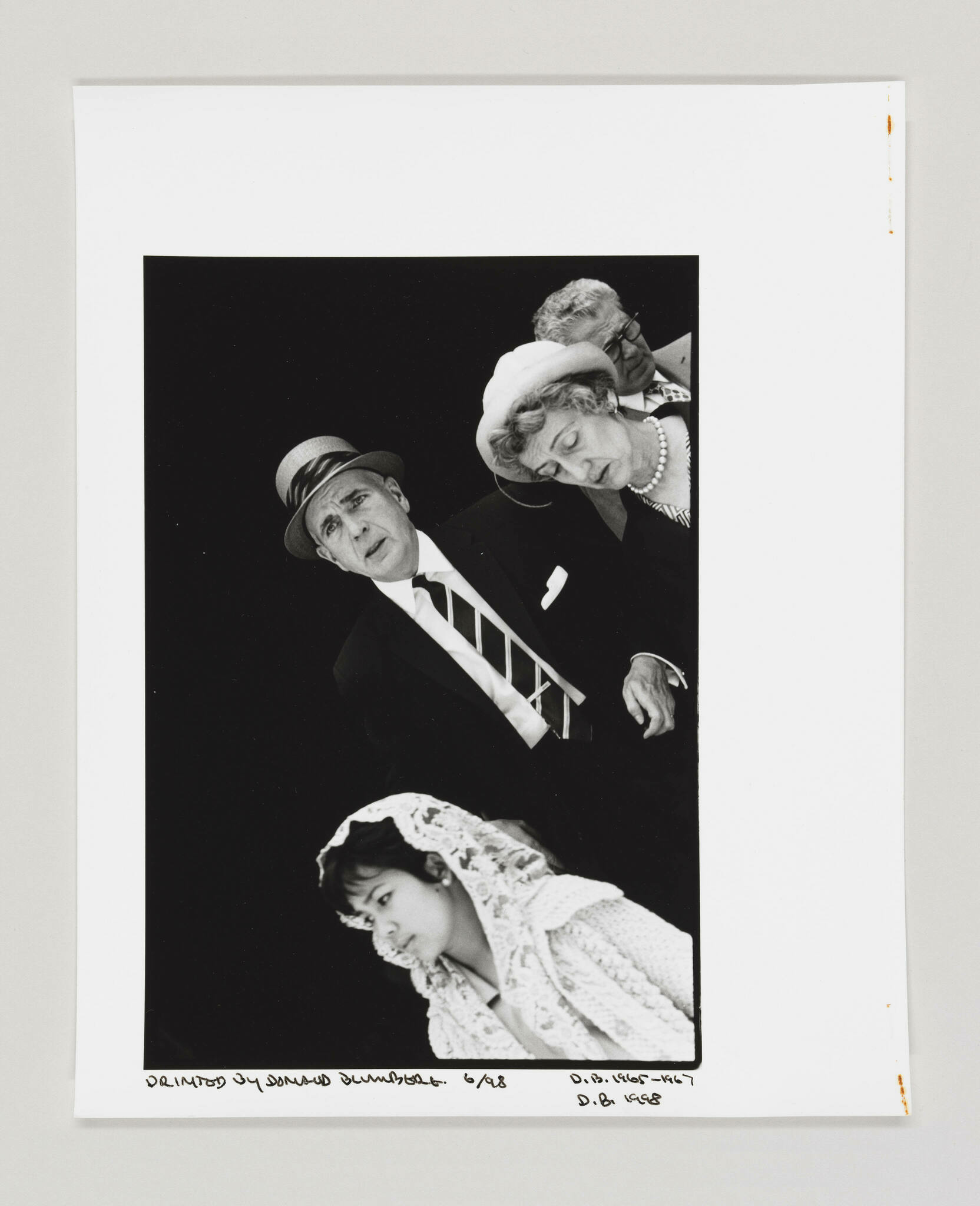 A black and white collage featuring three cut-out images of people against a black background, mounted on white paper. The top left shows a man in a suit and hat with a puzzled expression, the top right a woman in a hat and pearls looking down with a somber expression, and the bottom a young woman in a lace headscarf looking downward. Handwritten text and numbers are visible at the bottom of the white paper.