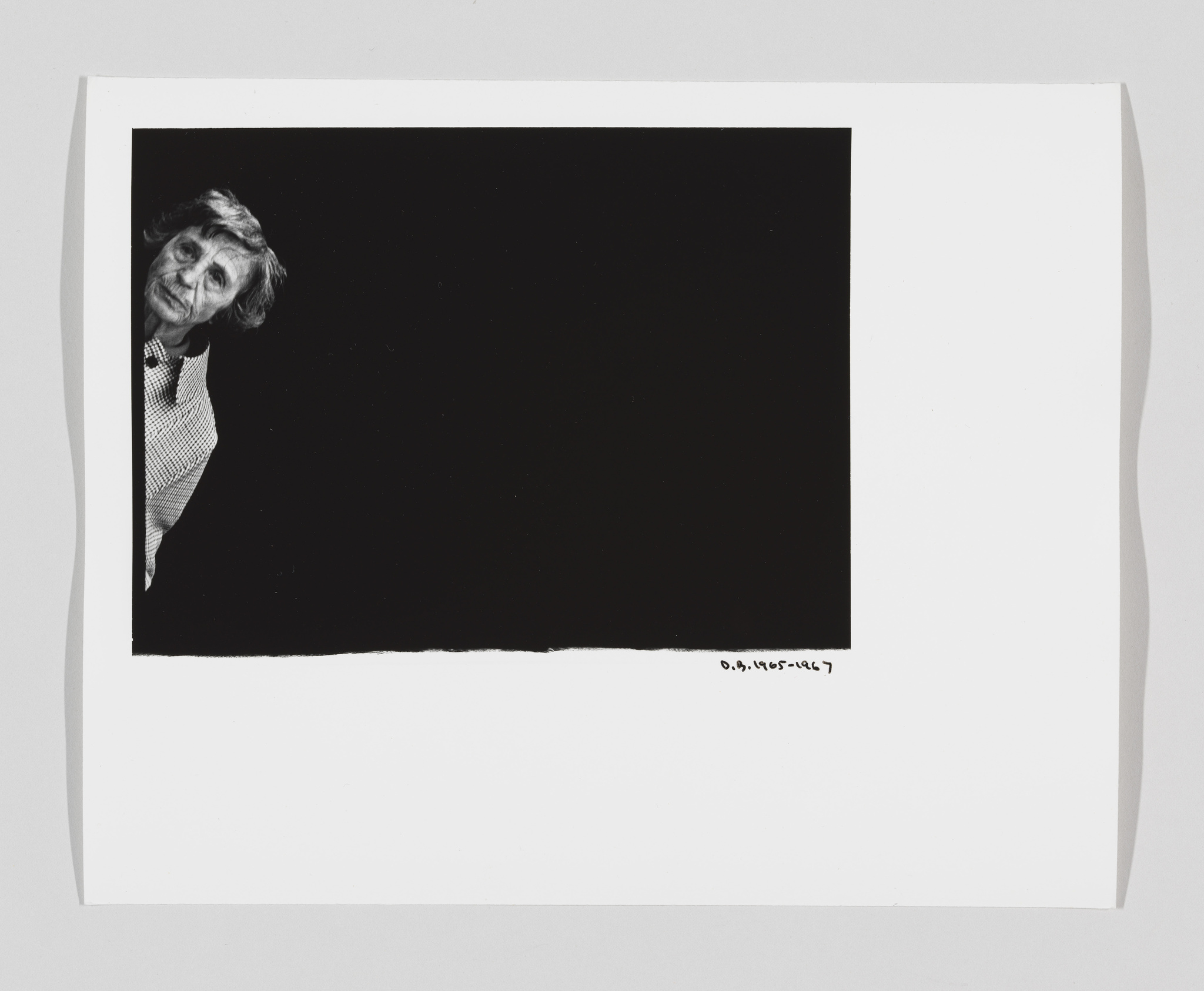 A black and white artwork featuring a partial portrait of an elderly woman peeking out from the edge of a dark square against a white background, with the artist's signature and a date at the bottom right corner.