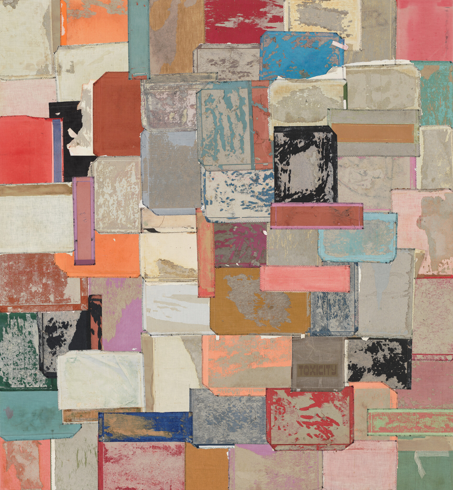 Patchwork of worn, colorful fabric rectangles stitched together in a rough geometric collage.