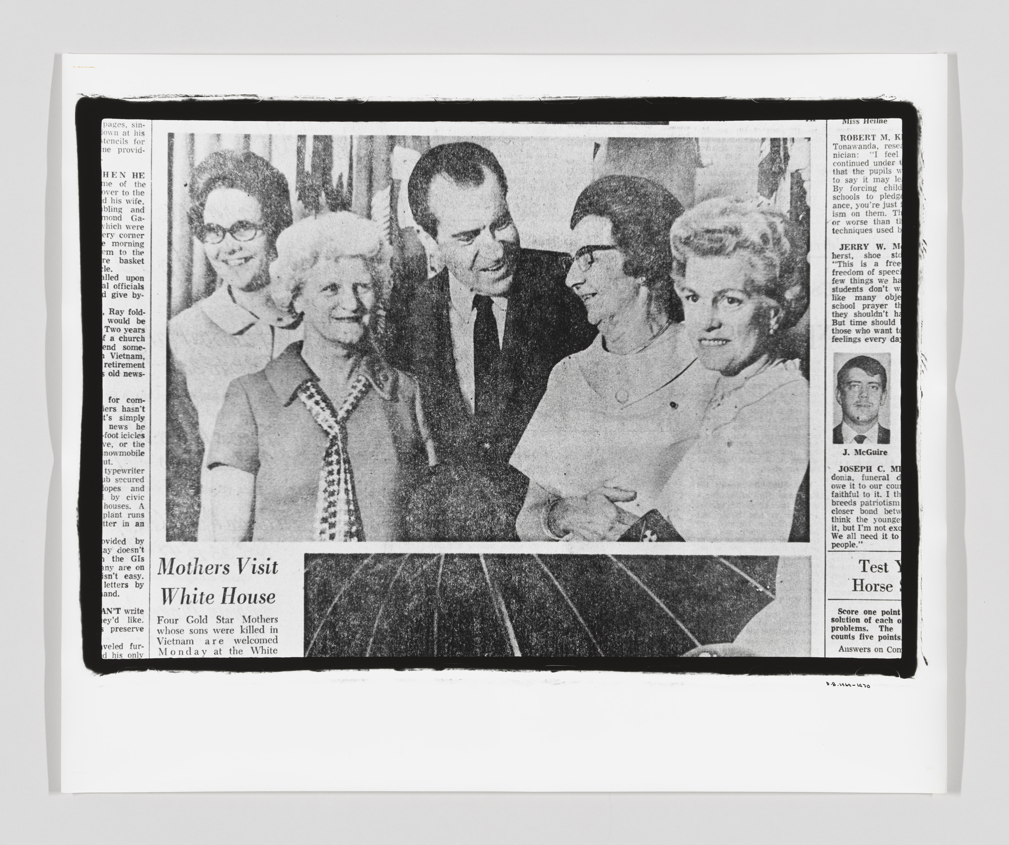 A black and white newspaper clipping featuring a group of four women and a man in a suit smiling and standing close together. The headline "Mothers Visit White House" is visible above the photo, and the article mentions "Four Gold Star Mothers whose sons were killed in Vietnam are welcomed Monday at the White House." The newspaper is slightly crumpled and placed on a white background.