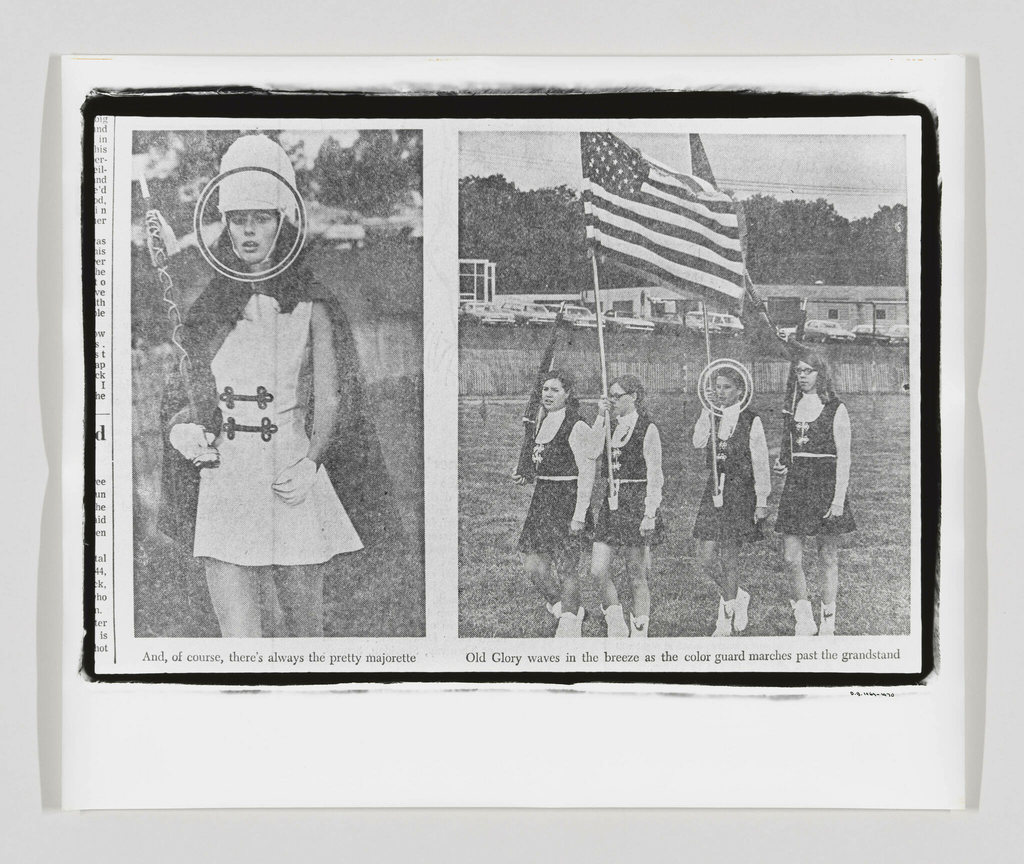 A black and white newspaper clipping featuring two images. On the left, a young woman dressed as a majorette with a baton and a helmet-like hat, with the caption "And, of course, there's always the pretty majorette." On the right, four individuals in uniform carrying flags, including the American flag, with the caption "Old Glory waves in the breeze as the color guard marches past the grandstand." The paper appears slightly crumpled and is set against a white background.