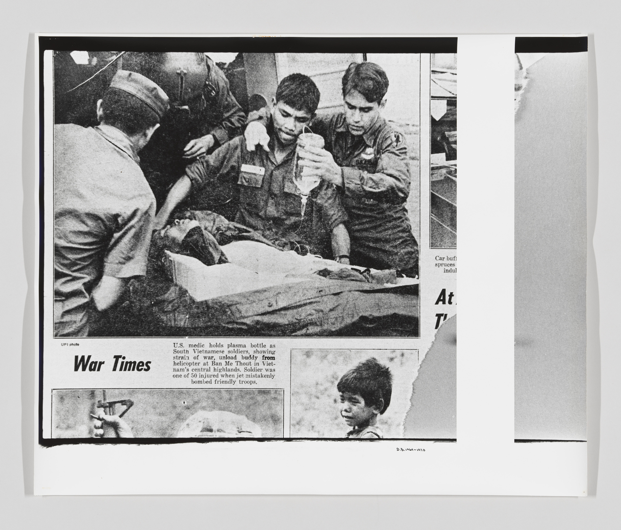 A black and white photo of a newspaper clipping showing a scene with medical personnel attending to a wounded soldier. The headline "War Times" is visible, and there is a caption describing the scene as a U.S. medic holding a plasma bottle for a wounded buddy in Vietnam. The image is slightly curled at the edges, indicating it is a physical copy of a newspaper page.